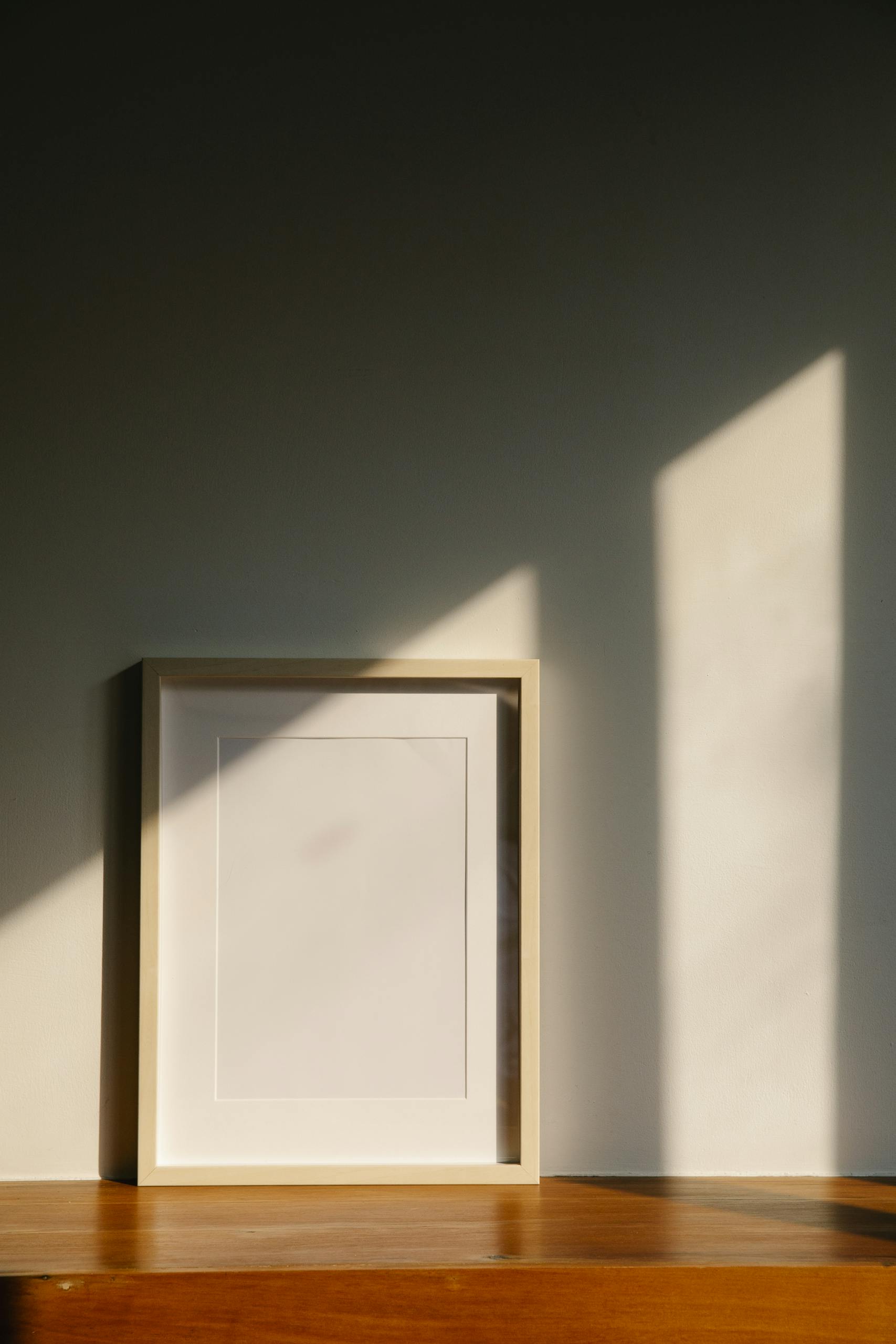 Elegant minimalist frame on a wooden shelf, bathed in warm sunlight. Perfect for interior decor concepts.